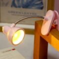 Mini clip-on book reading light clipped to a table edge with warm LED glow