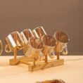 Six glass cups hanging on the wooden stand of the beverage set