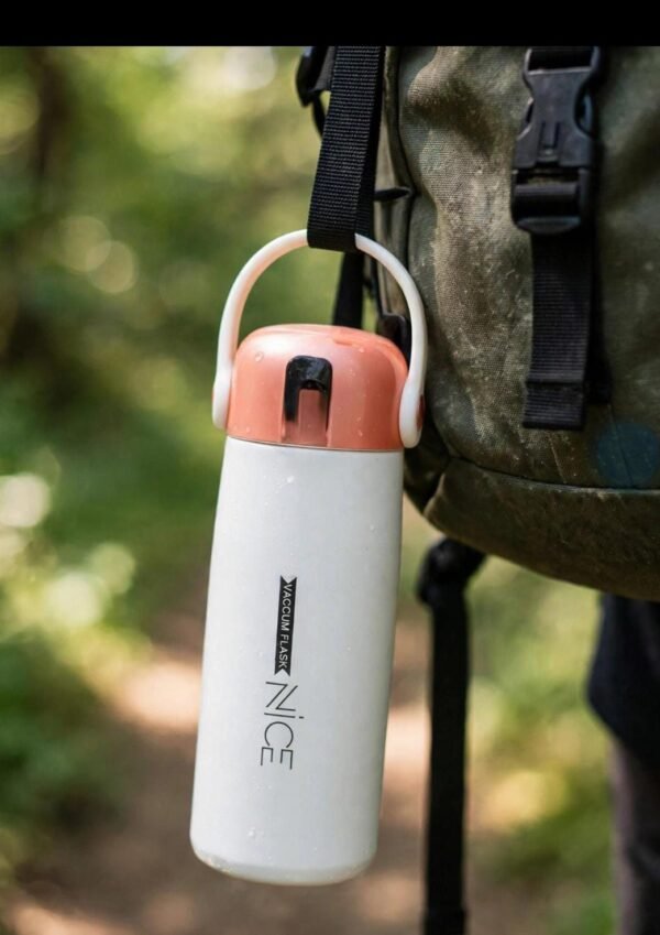 White insulated bottle hanging from a bag strap outdoors