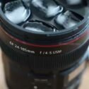 Camera lens travel mug filled with iced coffee close-up