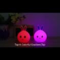 Two bunny silicone lamps glowing pink and purple on a shelf