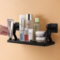 Black human figure wall shelf holding bathroom bottles